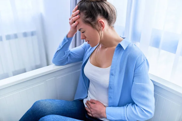 Adet ve ağrı periyodundan muzdarip hasta bir kadın. Gastrointestinal sistem hastalığı yüzünden karın ağrısı çeken bir kadın. İltihap ve enfeksiyon mesanesi, sistit.