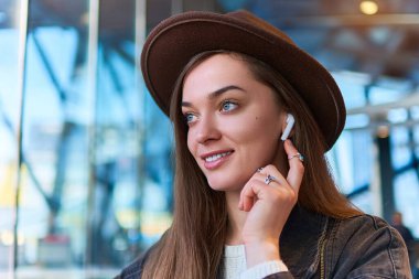 Moda modasına uygun hippi kadın portresi. Kablosuz kulaklıklı sıradan kadın şapkası. Dijital yaşam tarzı ve modern insanlar