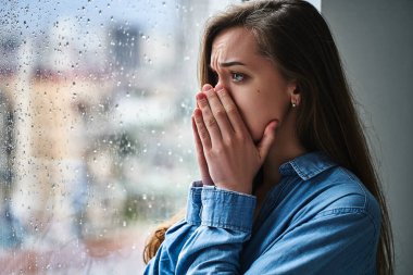 Stresli, üzgün, kederli, melankolik bir kadının portresi. Üzüntü, duygusal şok ve yaşam sorunları sırasında ağzı ellerle kaplayan bir kadın. 