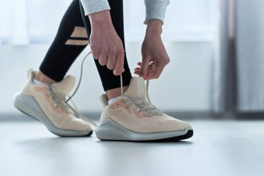 Spor salonundaki kadın ayakkabı bağcıklarını bej spor ayakkabılara bağlıyor ve koşuya ve antrenmana hazırlanıyor. Spor yap ve formda ol. Sportif yaşam tarzı olan spor insanları.    