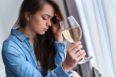 Üzgün, bunalımlı, şarap kadehiyle içki içen kadın akşamdan kalma ve baş ağrısı çekiyor. Kadın alkolizmi ve hayat sorunları, depresyon sırasında alkol bağımlılığı ve endişeler 