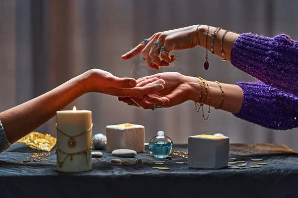 Magic gypsy woman reading palm lines around candles and other magical accessories. Witch during fortune telling palmistry, prediction the future life and divination ritual