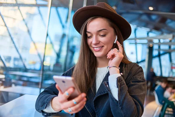 패션의 모자를 카페에서 전화와 헤드폰을 사용하여 온라인 음악을 듣는다 디지털 — 스톡 사진