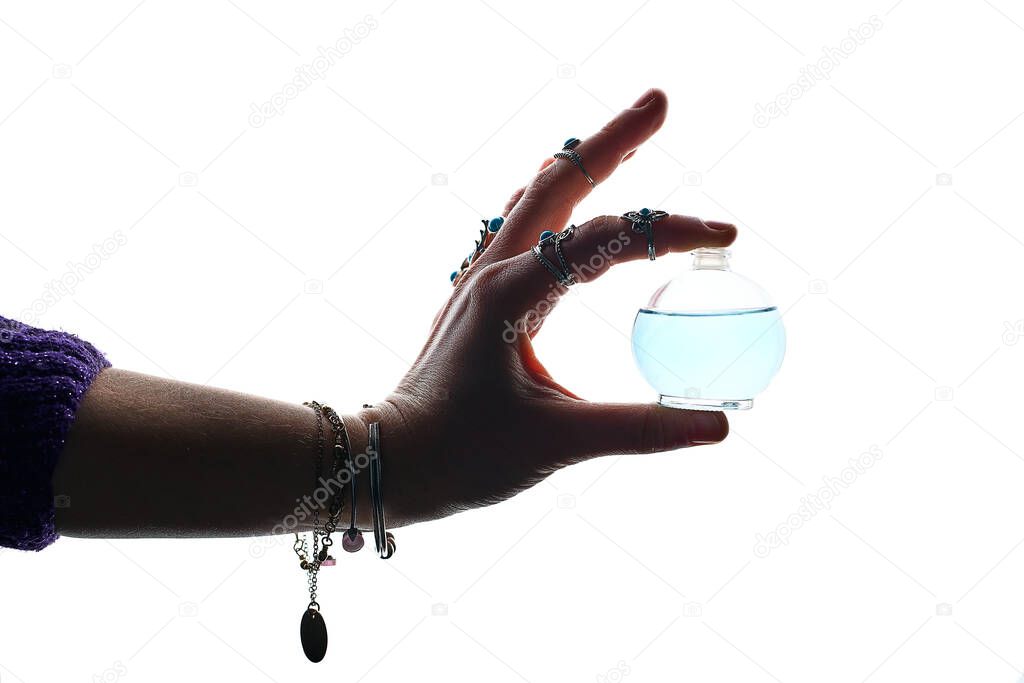 Crystal elixir potion bottle for love spell, witchcraft and divination in perfumer woman hands wearing silver rings and bracelets on a white background. Alchemy and perfumery