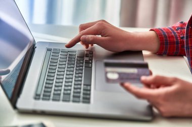 Bilgisayarı ve kredi kartını online alışveriş ve ödeme için kullanan kişi. E-ticaret ve mobil ödeme bankacılığı kullanan modern insanlar