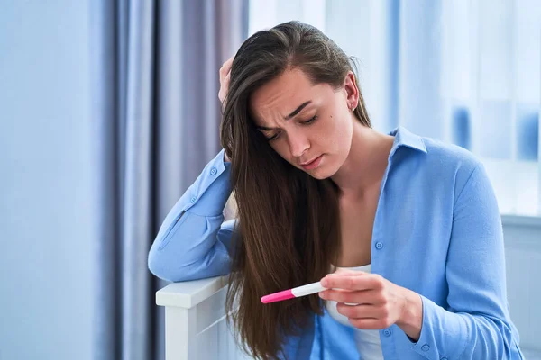 Sad frustrated unhappy woman holds a negative pregnancy test result