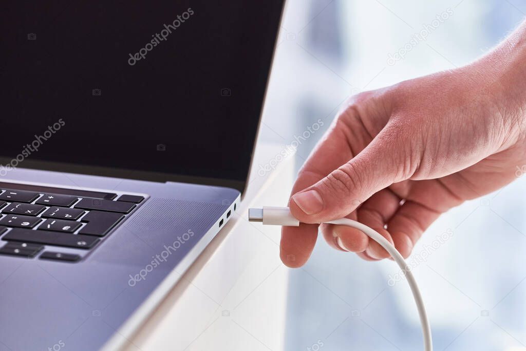 Laptop charger in hands close up. Discharged battery at computer 