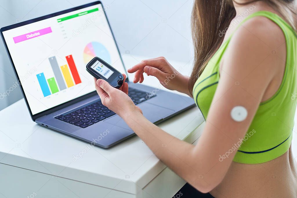 Diabetic patient using remote sensor and computer for control, online monitoring and examining glucose blood levels graphs. Medical technology in diabetes treatment
