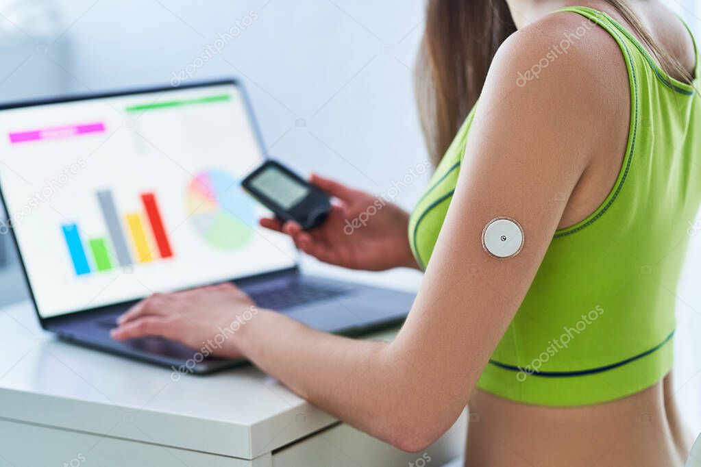 Diabetic patient using remote sensor and computer for examining and online monitoring glucose blood levels graphs. Diabetes control and healthcare