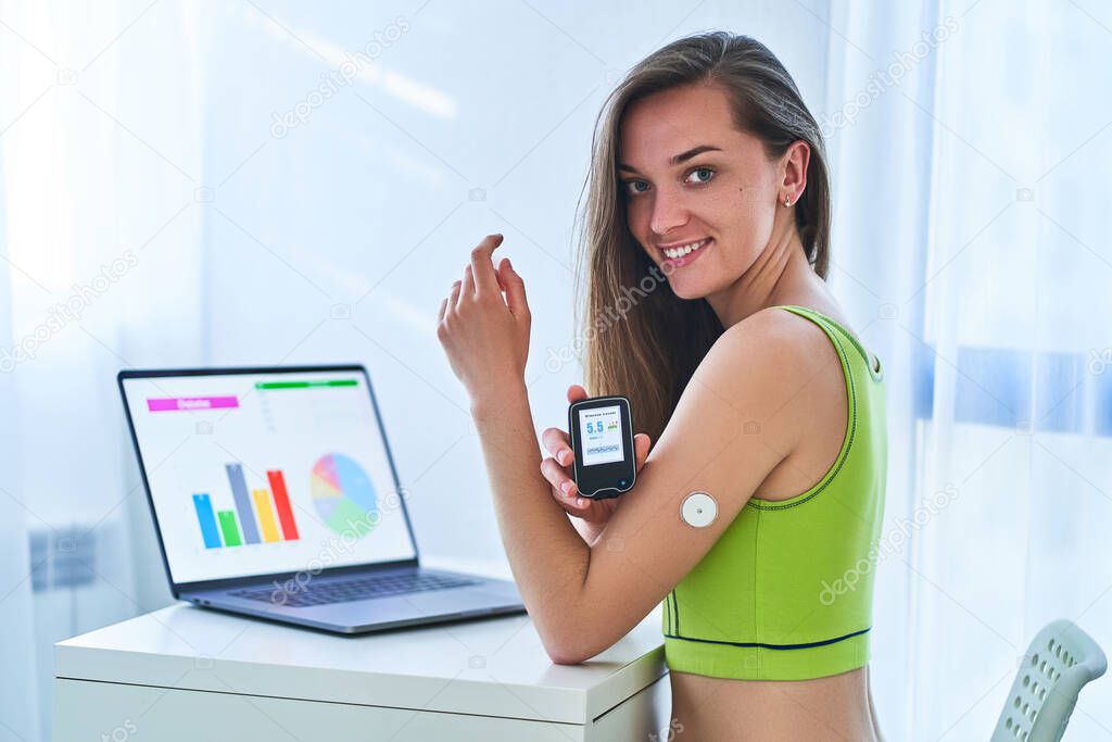 Woman suffering from sugar diabetes using remote sensor and computer for control, monitoring and examining glucose blood levels diagrams and graphs. Diabetics lifestyle