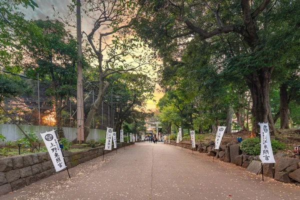 stock image tokyo, japan - october 20 2020: Path decorated of japanese pennants with the coat of arms of Tokugawa Shoguns and leading to the stone torii gate of the Ueno Tosho-gu shrine dedicated to first Shogun.