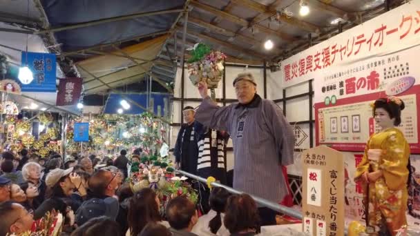 Tilt-up-Video japanischer Frauen im Kimono und Männer in Happi-Jacke bei einer Auktion auf der Tori-no-Ichi-Messe des Ootori-Schreins. — Stockvideo