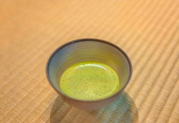 Background of a ceramic ware Chawan Cup of Japanese Matcha green tea on a tatami mat covered with woven soft rush straw in a traditional Japanese-style room.