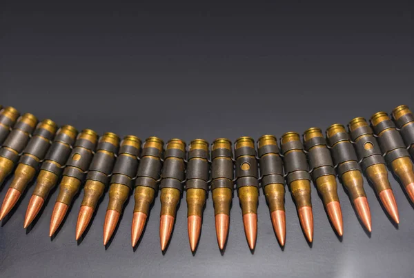 Bullets suitable for M80/M62 which are linked ammunition consisting of Lake City brass, links, boxer-primers and projectiles lined up in row on a black background.