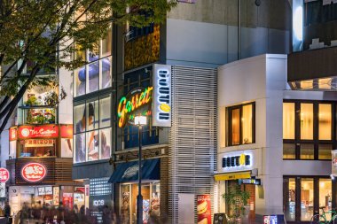 Tokyo, Japonya - Kasım 05 2020: Omotesando Bulvarı 'ndaki göz alıcı reklam tabelaları ve pankartlarla aydınlatılmış mağaza ve mağazaların gece görüşü.