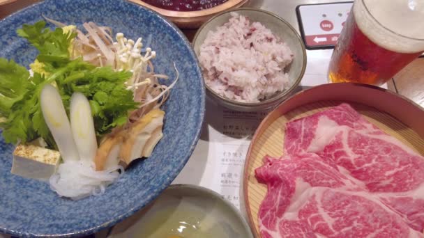 Panela quente Sukiyaki japonês com ovo cru, carne fatiada, legumes e arroz. — Vídeo de Stock