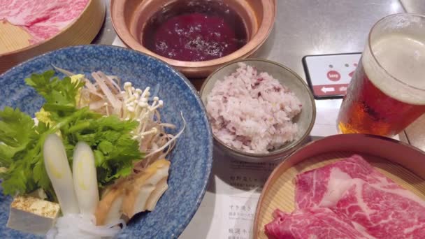 Japonský Sukiyaki horký hrnec se syrovým vejcem, nakrájeným masem, zeleninou a rýží. — Stock video