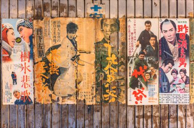 Tokyo, Japonya - 26 Ocak 2021: Yurakucho İstasyonu 'nun paslı metal duvarında yakuza ve samuray retro filmlerinin yırtılmış eski ve klasik Japon posterleri.