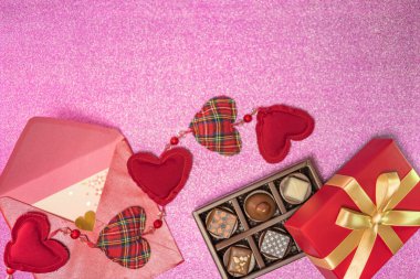 Sevgililer Günü 'nü kutlamak için üzerinde altın kurdele ve pembe bir arkaplan bulunan bir aşk mektubuyla süslenmiş çikolata kutusunu gösteren tebrik kartı..