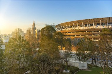 Tokyo, Japonya - 8 Şubat 2021: 2020 Olimpiyat ulusal stadyumunun arka planda NTT Docomo Yoyogi Binası bulunan Japon olimpiyat meydanı önündeki yüksek açılı günbatımı manzarası.