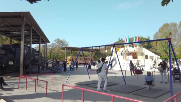 2019年11月5日 日本东京 日本家庭和孩子们在Asukayama公园游乐场广场玩荡秋千和滑梯的泛右面视频 该公园以其古老的蒸汽火车和有轨电车而闻名 — 图库视频影像
