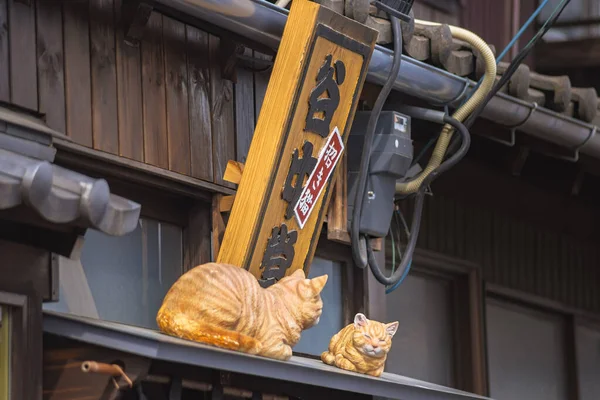 2021年4月20日 谷中銀座の谷根千地区にあるレトロな喫茶店 Manekineko Yanakado の名前で2匹の猫の彫刻と木彫りの看板を閉じます — ストック写真