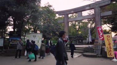 Tokyo, Japonya - 20 Ekim 2019 Ueno Tosho-gu türbesini ziyaret eden turistlerin videosu önemli bir kültürel mülk olarak sınıflandırıldı ve Toshogu Daiichi Dükkanı 'nın yanındaki taş torii kapısının altından geçiyordu..