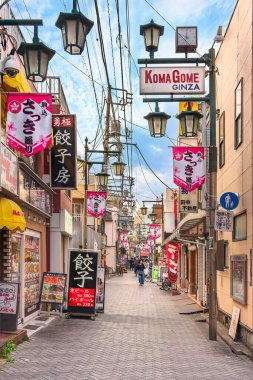 Tokyo, Japonya - Nisan 07 2019: Komagome Satsuki alışveriş caddesi anlamı Rhododendron çiçek caddesi Japon flamalarıyla süslenmiş ve gyoza restoranları ve dükkanlarına bakan retro sokak ışıkları.