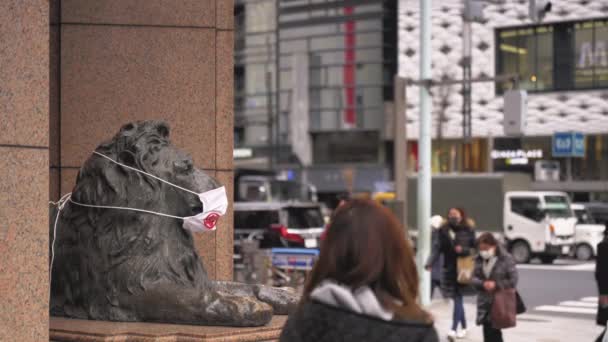 東京都 2021年1月8日 コロナウイルス大流行時にマスクを着用した銀座三越のライオンのブロンズ像のビデオ歩行者が横を歩く — ストック動画