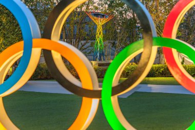 tokyo, japan - may 10 2021: Close up on the illuminated Olympic Cauldron of Nagano Olympic Winter Games through the color circles of the Olympic Rings monument lighted up at japan sport olympic square clipart