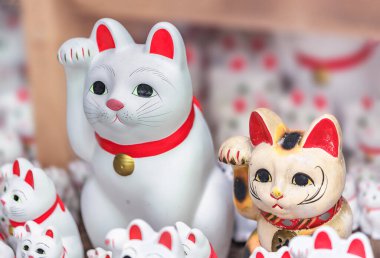 Sağdaki geleneksel Japon manekinekosu ve soldaki Budist tapınağına adanmış maneki-neko 'nun boynunda bozuk para değil, çanı var.