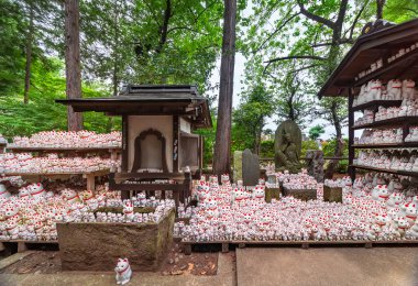 Tokyo, Japonya - 25 Haziran 2021 Bodhisattva Avalokitesvara 'nın, Japonca' da Nyoirin Kannon Bosatsu adı verilen bir heykeli Budist gotokuji tapınağında bir grup manekinekoyla çevrili..