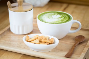 Beyaz fincan yeşil çay bir aperatif ile ahşap bir tepsi  