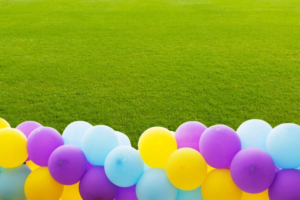 Fresh spring green grass with colorful balloon — Stock Photo, Image