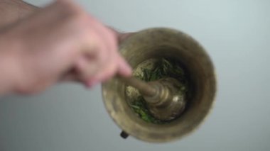 Bakır kasede tarhun ezen bir adam bitkisel tentür üretiyor.
