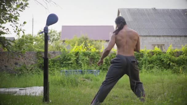 Hombre atlético con el pelo largo y negro y un hermoso torso, práctica karate en el jardín, la práctica de patadas — Vídeos de Stock