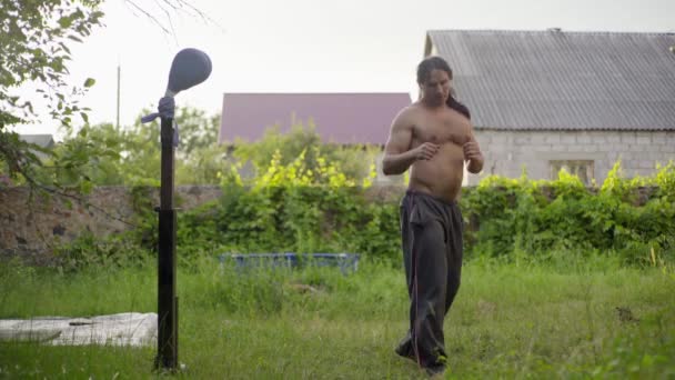Hombre de pelo negro largo y un hermoso torso, artes marciales prácticas en el jardín, patadas practicantes — Vídeo de stock