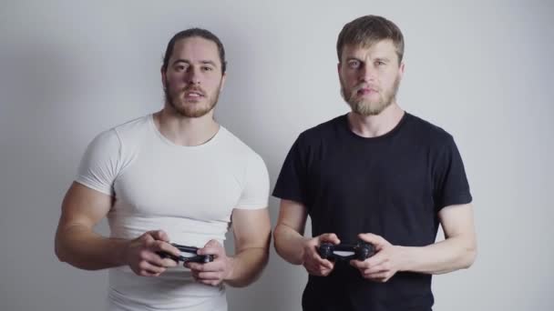 Dois caras, jogadores, jogar futebol intensamente em um console de videogame, segurar joysticks em suas mãos — Vídeo de Stock