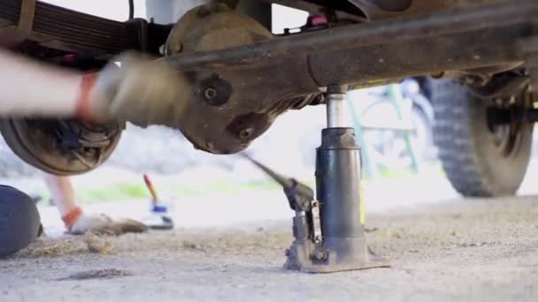 Jack, gros plan sur les mains des hommes, on soulève la voiture — Video