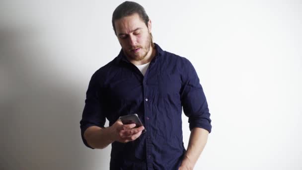 Um homem de barba vermelha e cabelo comprido, de camisa azul e jeans, sobre fundo branco — Vídeo de Stock