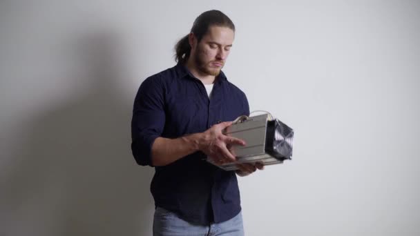A man looks at an asic for mining, bitcoin, does not understand what to do with it — Stock Video