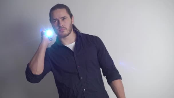 Security guard with a red beard and long hair, an athlete, shines with a flashlight — Stock Video