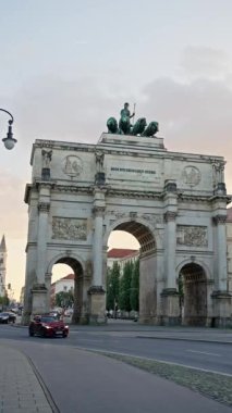 Münih, Almanya - 03 Ekim 2025: Münih 'teki Siegestor veya Zafer Kapısı, Bavyera' nın aslan kuadrigası ile taçlandırılmış bir anıt kemeridir. Anıtın etrafındaki caddede trafik vardı. 4k