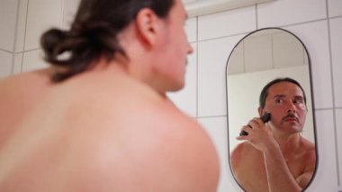Bir adam duşta tıraş oluyor, özen gösteriyor ve modern tımar alışkanlıkları sergiliyor. Yüksek kalite 4k görüntü