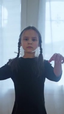 Genç bir kız, zarif bir şekilde poz verdi, zarif duruşunu ve sıcak, yumuşak bir ışıkla etkileyici hareketini sergiledi. Bir kız çocuk, ünlü bir filmden hareketlerini tekrarlayarak enerjik bir şekilde dans eder. 4k