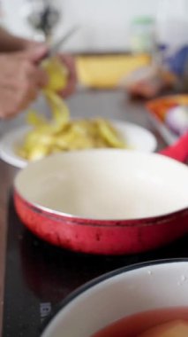 Patates soyuluyor, patates soyuluyor, patates soyuluyor, ellerin çanak çömleğin üzerinde patates soyuluyor, şef mutfak tezgahında patatesleri doğal ışık ile kabın içine soyuyor.