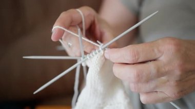 Çift renkli iğneler ve yumuşak ipliklerle ustalıkla örülmüş, samimi ve sıcak bir ortamda iki elin yakın çekimi. Yüksek kalite 4k görüntü
