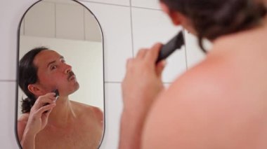 Bir adam duşta tıraş oluyor, kendine özen gösteriyor ve modern tımar alışkanlıkları sergiliyor. Yüksek kalite 4k görüntü