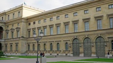 Antik bina manzarası, ziyaretçiler kapalı hava koşulları altında tarihi mimarinin fotoğraflarını çekiyorlar, güvenlik görevlileri turistlerin görüntüleri çekerken antik saray girişinde devriye geziyorlar.