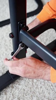 Kilit mandalını döndüren ve pirinç düğmeyi sıkılaştıran metal çerçeveyi ayarlayan yakın plan eller, turuncu kollu montajcı dikkatlice, adımlı araç gereçleri kullanarak tabana hizalanıyor. 4k